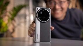A person holding a Xiaomi 15 Ultra smartphone, smiling with greenery in the background.